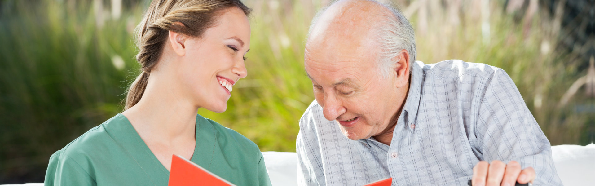 nurse and elderly man reading